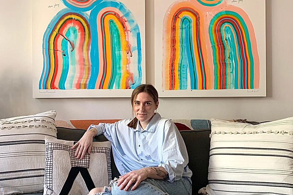 Artist Amber Vittoria in her home under two of her signature artworks.